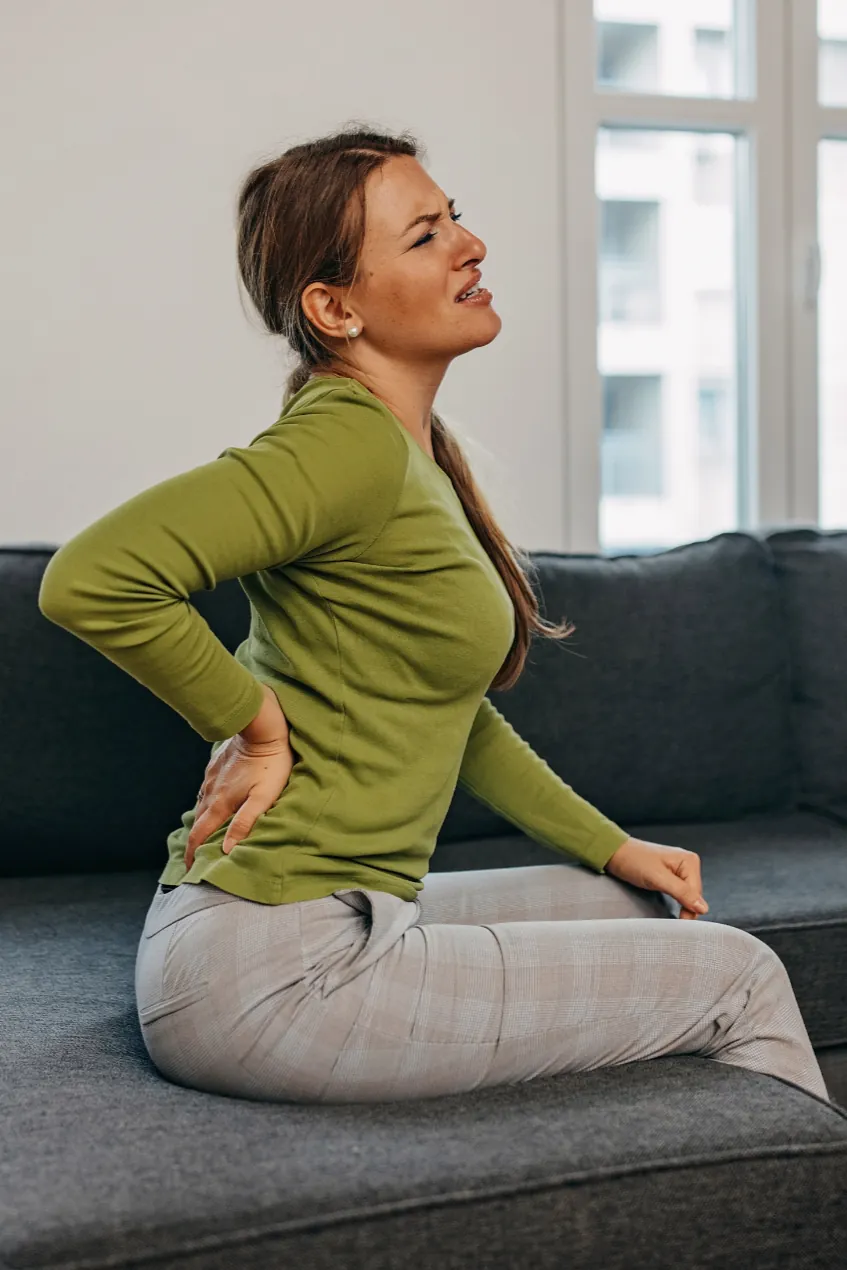 Mujer con dolor lumbar en casa. Acupuntura en Tenerife para aliviar dolor de espalda y recuperar equilibrio y bienestar con terapia personalizada.